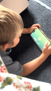 A young girl gives a thumbs up while holding a tablet in a colorful case, engaging in digital learning.